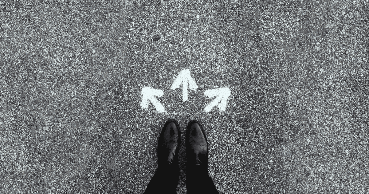Three chalk arrows pointing in different directions in front of a pair of shoes