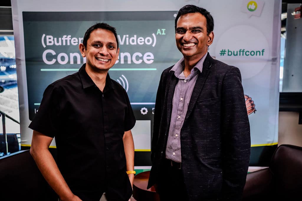 Buffer-Free Video AI カンファレンスのバナーの前で一緒に写真に収まる 2 人の参加者。