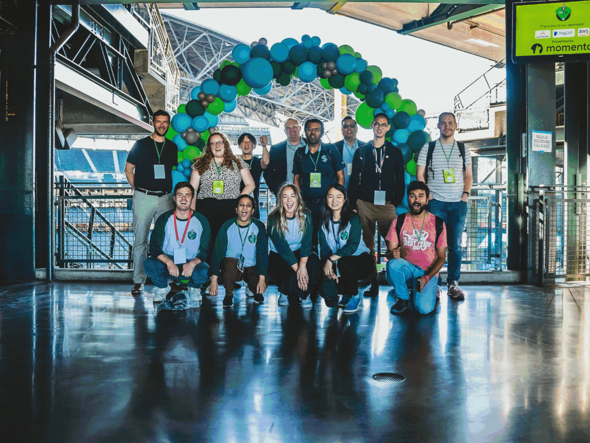 Momento team posing beneath a balloon arch at MoCon 2023.