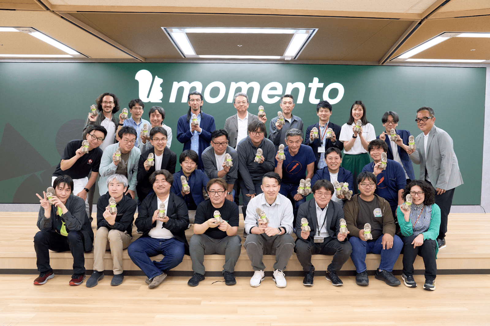 Momento の背景の前で記念撮影する大勢の参加者