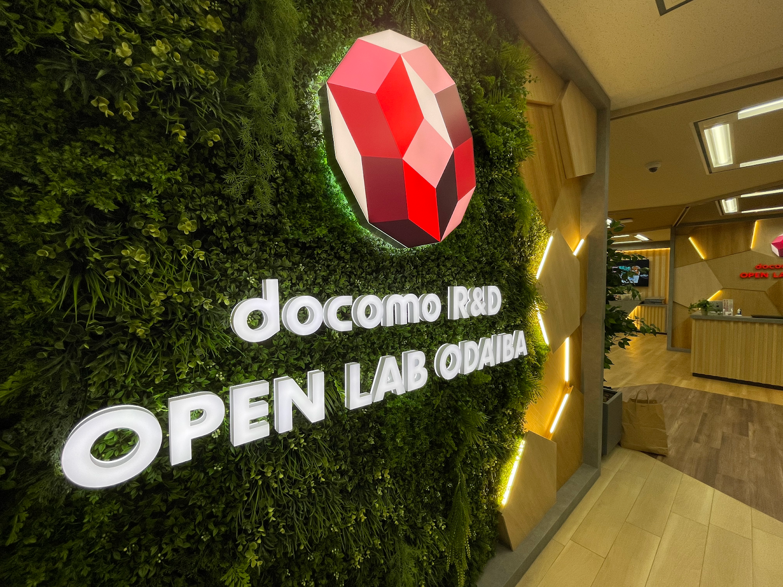 緑の壁に掲げられた docomo R&D OPEN LAB ODAIBA の入口看板。