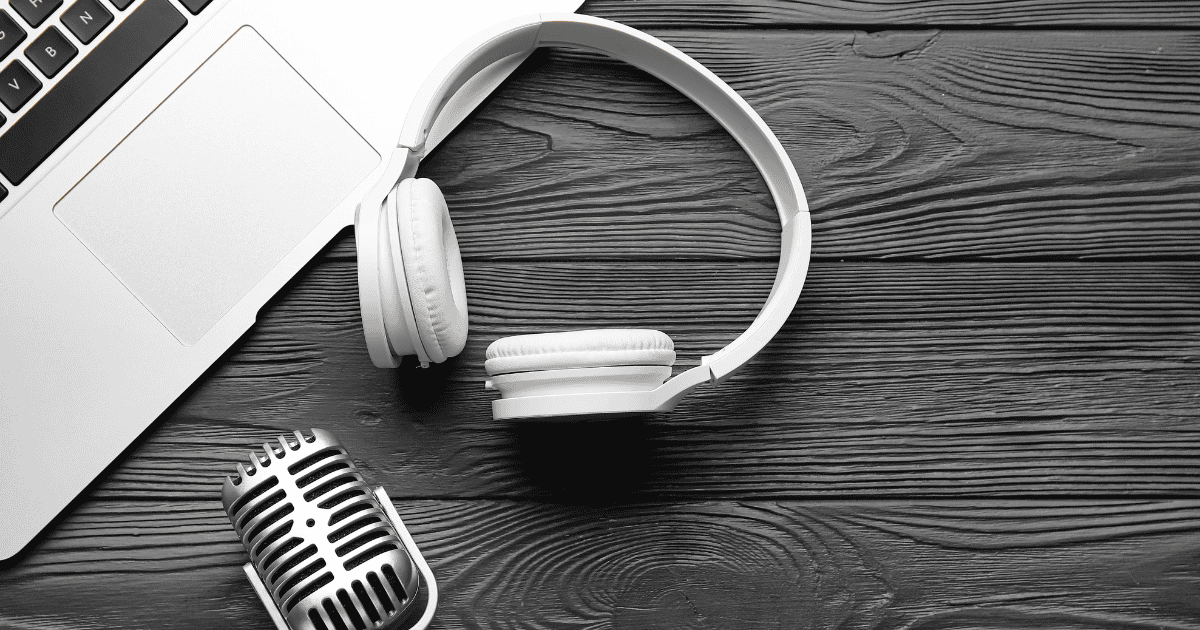 A laptop, headphones and microphone on a wooden desk