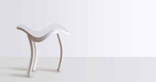 A white curved stool on a pale background
